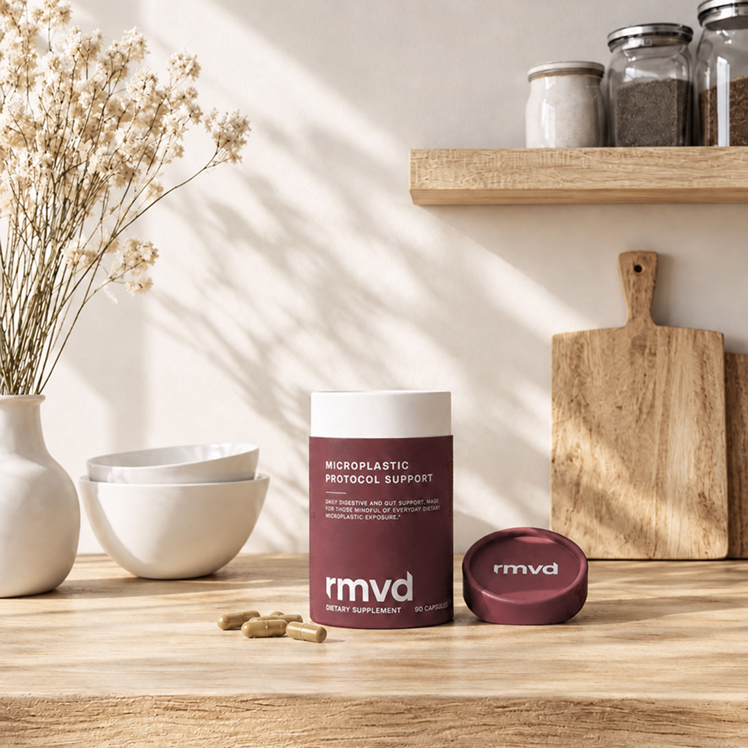 rmvd tube and lid on a sunlit wooden kitchen counter with three loose capsules, stacked bowls and dried flowers